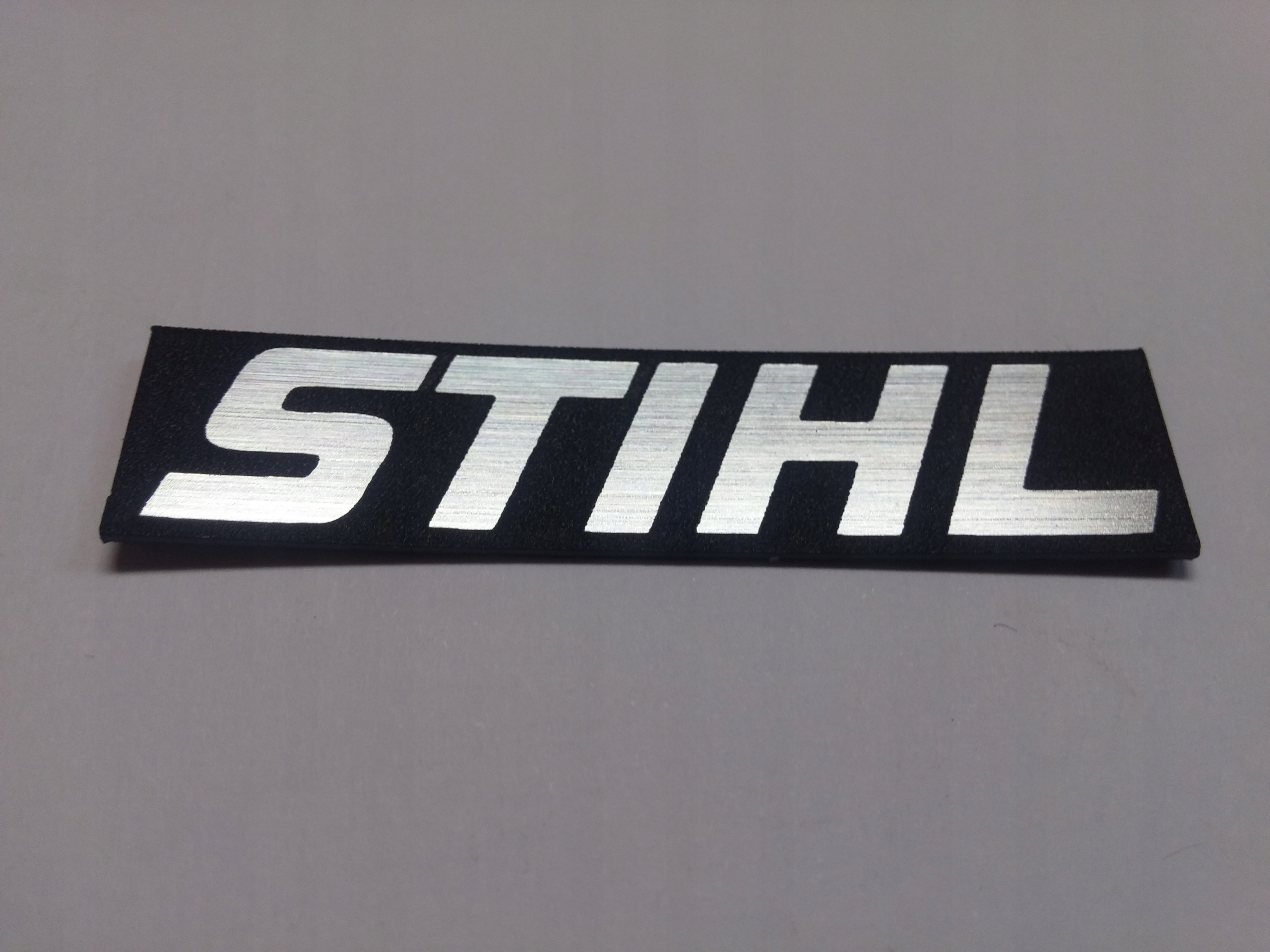 

Stihl naklejka emblemat 56 x 13 mm*SREBRNA