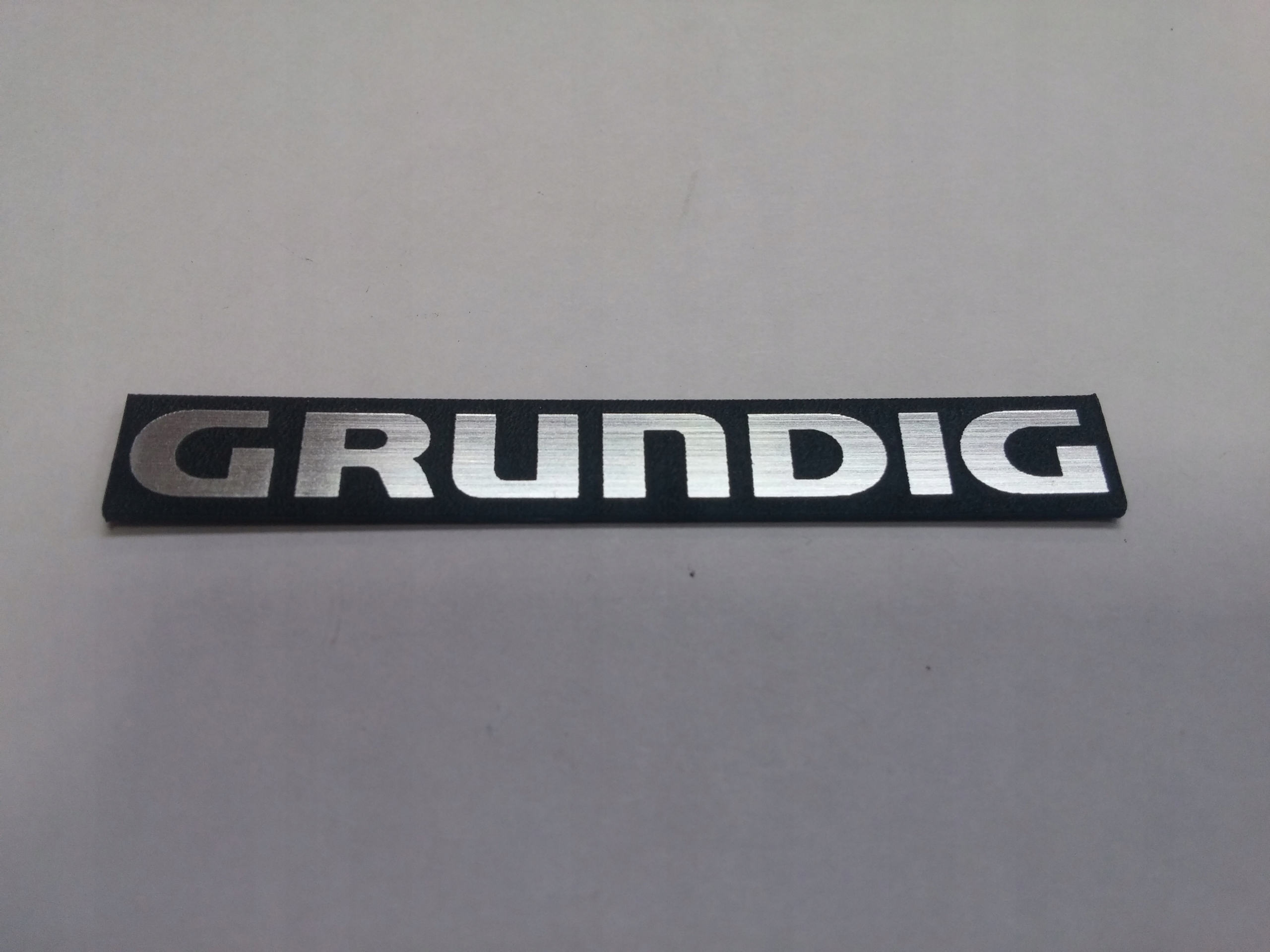 

Grundig naklejka emblemat 120 x 14 mm * Srebrna