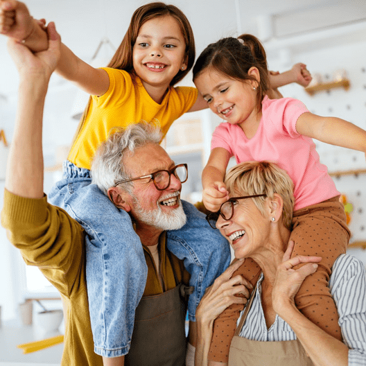 Family photo: Grandfather, grandmother, two young girls, yellow shirt, brown pants, smiling.
