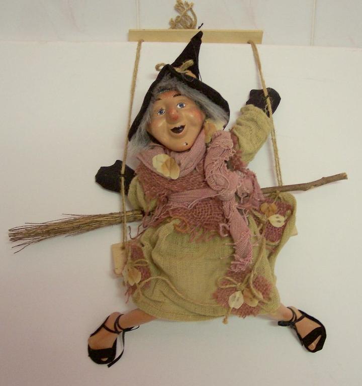 Wesoła czarownica Baba Jaga z miotłą na huśtawce