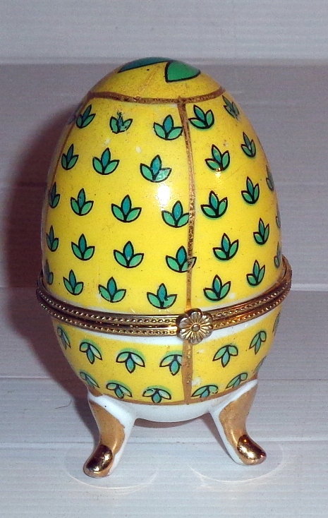Żółte porcelanowe puzderko w kształcie jajka .