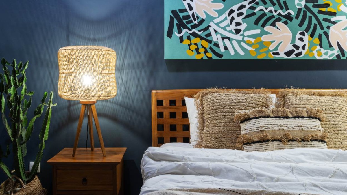 nočná lampa v boho štýle drevená posteľ na pozadí tmavomodrej steny