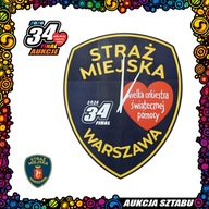 Duży zegar ścienny w kształcie naszywki Straży Miejskiej m.st. Warszawy