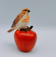mała figurka, kolorowy ptak siedzący na jabłuszku