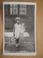 Mała dziewczynka i zabawki - lalka, mała konewka Stare zdjęcie.