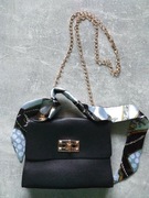 Mała czarna jednokomorowa torebka na łańcuszku.