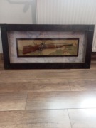 Obraz z repliką broni za szkłem 