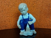 Porcelanowa figurka chłopca układającego klocki