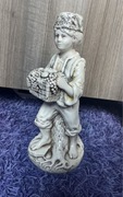 Figurka chłopiec z koszem winogron na pniu drzewa