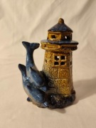 ceramiczna figurka przedstawiająca latarnię morską z delfinami