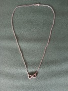 Srebrny łańcuszek ze znakiem nieskończoności.