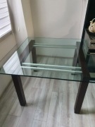 Solidny, szklany stół z ciemnymi, drewnianymi nogami. 