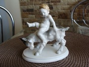 Figurka porcelanowa, Metler & Ortloff Putto na koziołku.