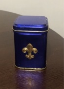 Zabytkowa , metalowa puszka , ozdobiona motywem złotej lilii