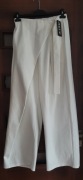 Białe spodnie z zakładką fartuszkiem plisa z paskiem klamerką