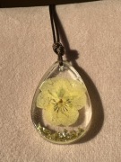 Kobiecy wisiorek z suszonym kwiatem.