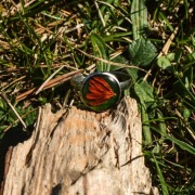 Pierścień z żywicy z pomarańczowym płatkiem na zielonym tle