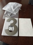 nowoczesny numer domu w kształcie cyfry trzy, wykonany ze szczotkowanej sta