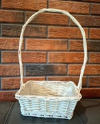 Biały koszyk wiklinowy z rączką.