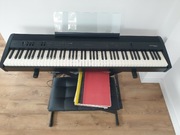 Pianino cyfrowe Roland FP-60X, ze statywem, krzesłem i z nutami.