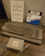 Commodore C64 z pokrywą zabezpieczającą, zasilaczem Ii dyskietką 