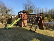 Drewniany domek dla dzieci z dwiema huśtawkami