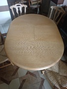 Rozkładany stół z 4 krzesłami z siedziskami wiklinowymi.