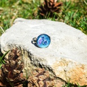 Pierścień z żywicy z fioletowymi kwiatami na niebieskim tle