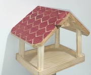 Czerwony drewniany karmnik dla ptaków. 