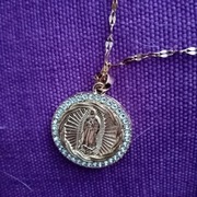 Łańcuszek z medalikiem z wizerunkiem MB z Gwadelupe w kolorze złotym. 