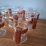 Osiem małych szklanek z miedzianymi uchwytami