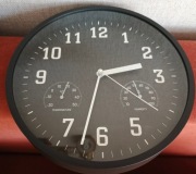 Czarny  zegar ścienny z termometrem i higrometrem.