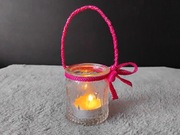 Szklany świecznik typu tealight z uchwytem z różowej wstążki.