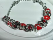 Bransoletka z metalowymi charmsami w czerwonej tonacji