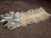 Podwiązka ślubna z koronki, ozdobiona błękitną kokardką