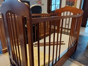 Łóżeczko dla dziecka wykonane z drewna w kolorze brąz. 