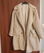 Beżowy płaszcz damski to model z imitacji baranka typu teddy coat