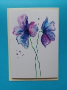 Kartka ręcznie malowana z fioletowo- niebieskimi kwiatami.