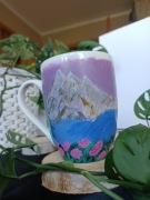 Kubek ręcznie malowany z krajobrazem górskim.