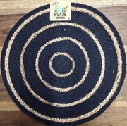 okrągła, czarno-naturalna mata dekoracyjna lub podkładka wykonana z juty. 