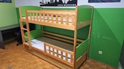 Drewniane łóżko piętrowe z zielonymi panelami i szufladą