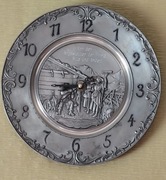 Zegar w kształcie metalowego talerza z płaskorzeźbą