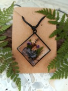 Wisiorek w czarnej oprawie z niebiesko fioletowymi kwiatami 