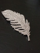 Piękna metalowa broszka piorka