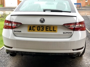 Логотип ŠKODA черного глянцевого цвета на багажнике.