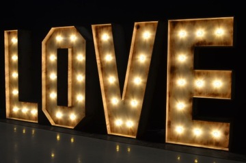 Надпись LOVE, выжженная на дереве, подсвеченная лампочками.