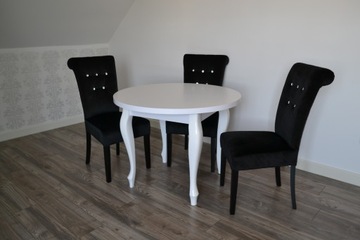 Круглый белый глянцевый стол на четырех ножках.