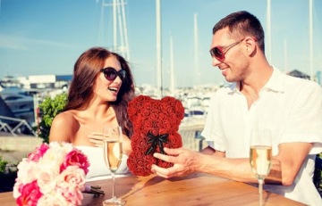 Мишка Тедди с лепестками роз в подарочной коробке ко Дню святого Валентина.