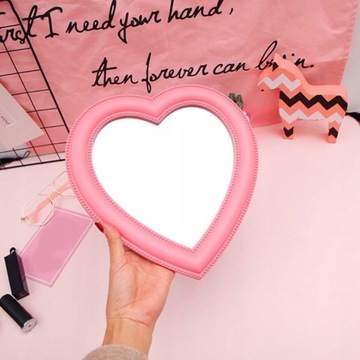 Розовое зеркало для макияжа на столе.