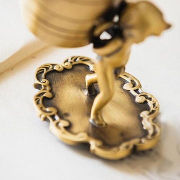 Ангел несет статую с корзиной, подставку для десертной ложки с фруктами.